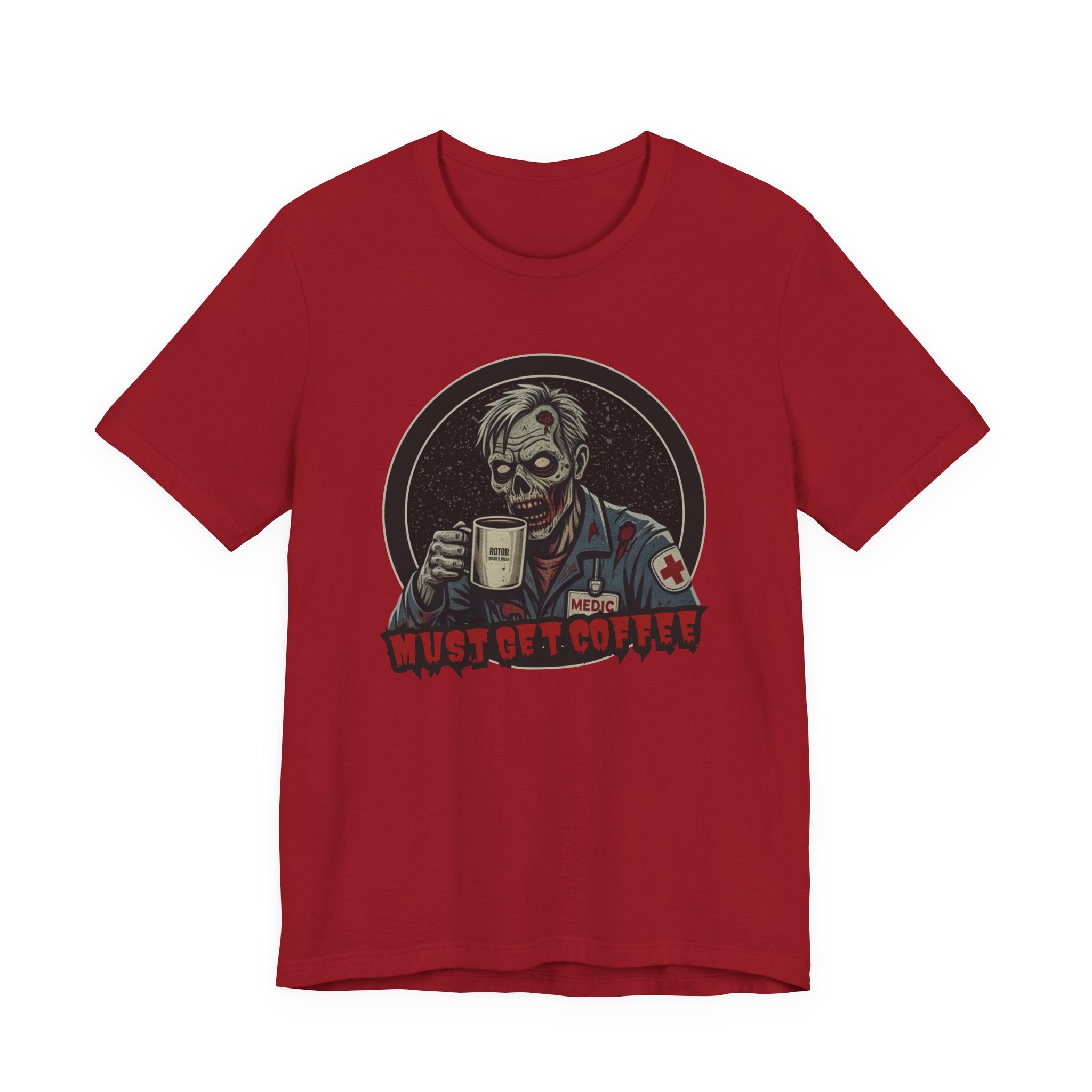 A red crewneck t-shirt featuring a graphic of a zombie medic holding a coffee mug with the text 'MUST GET COFFEE!' in red by Rotor Wash & Wear