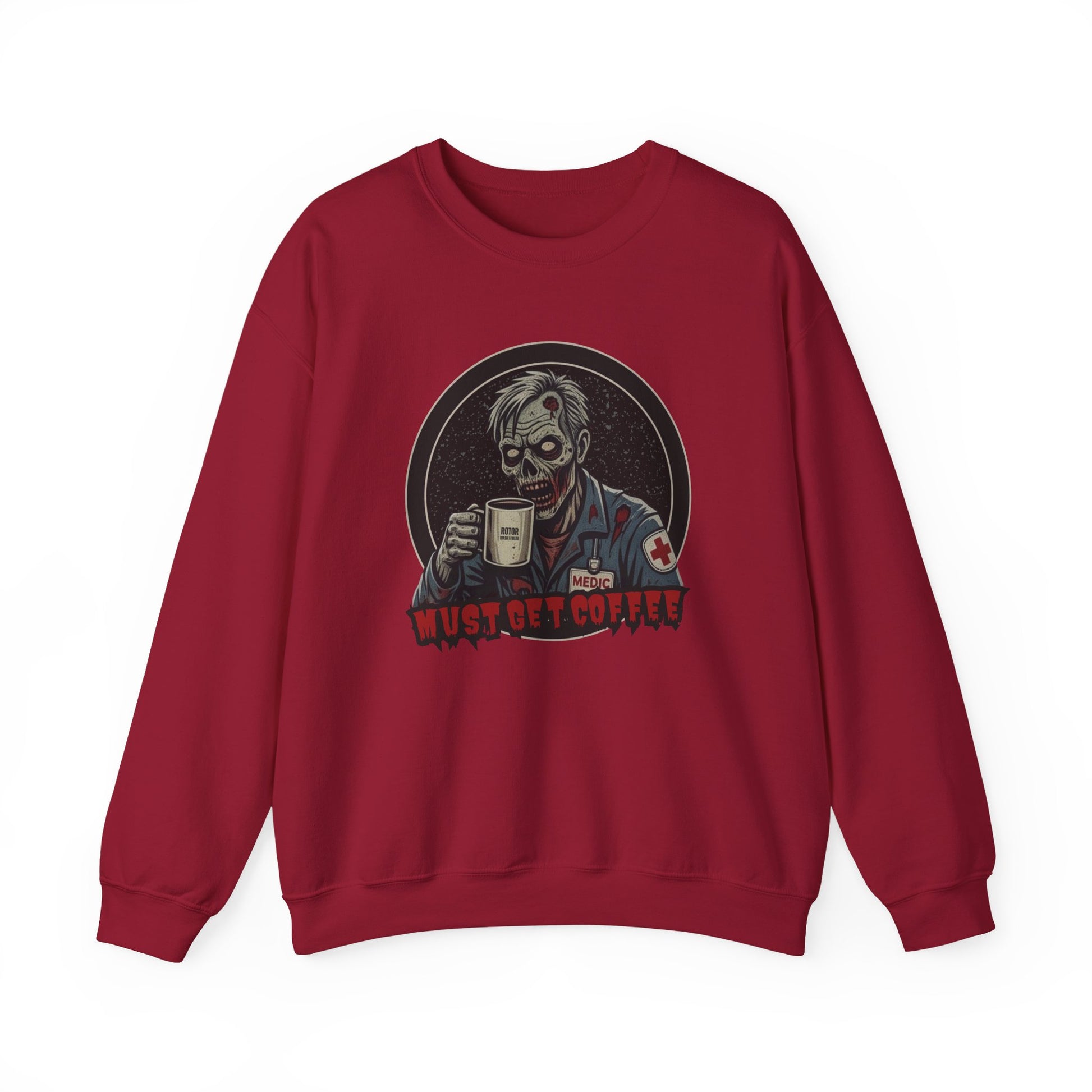 A red crewneck sweatshirt featuring a graphic print of a zombie in a medical uniform holding a coffee mug, with the text 'MUST GET COFFEE' below it by Rotor Wash & Wear