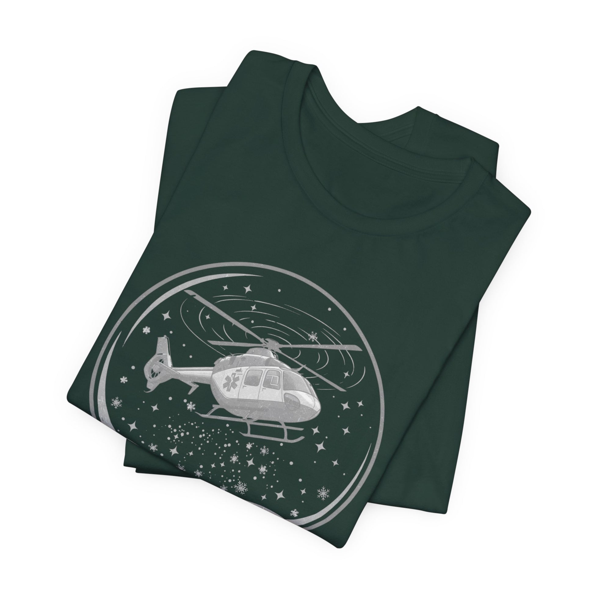 Folded dark green t-shirt with a graphic of a helicopter in a snow globe and text "Heli-bells ring: certified for the holidays" by Rotor Wash & Wear