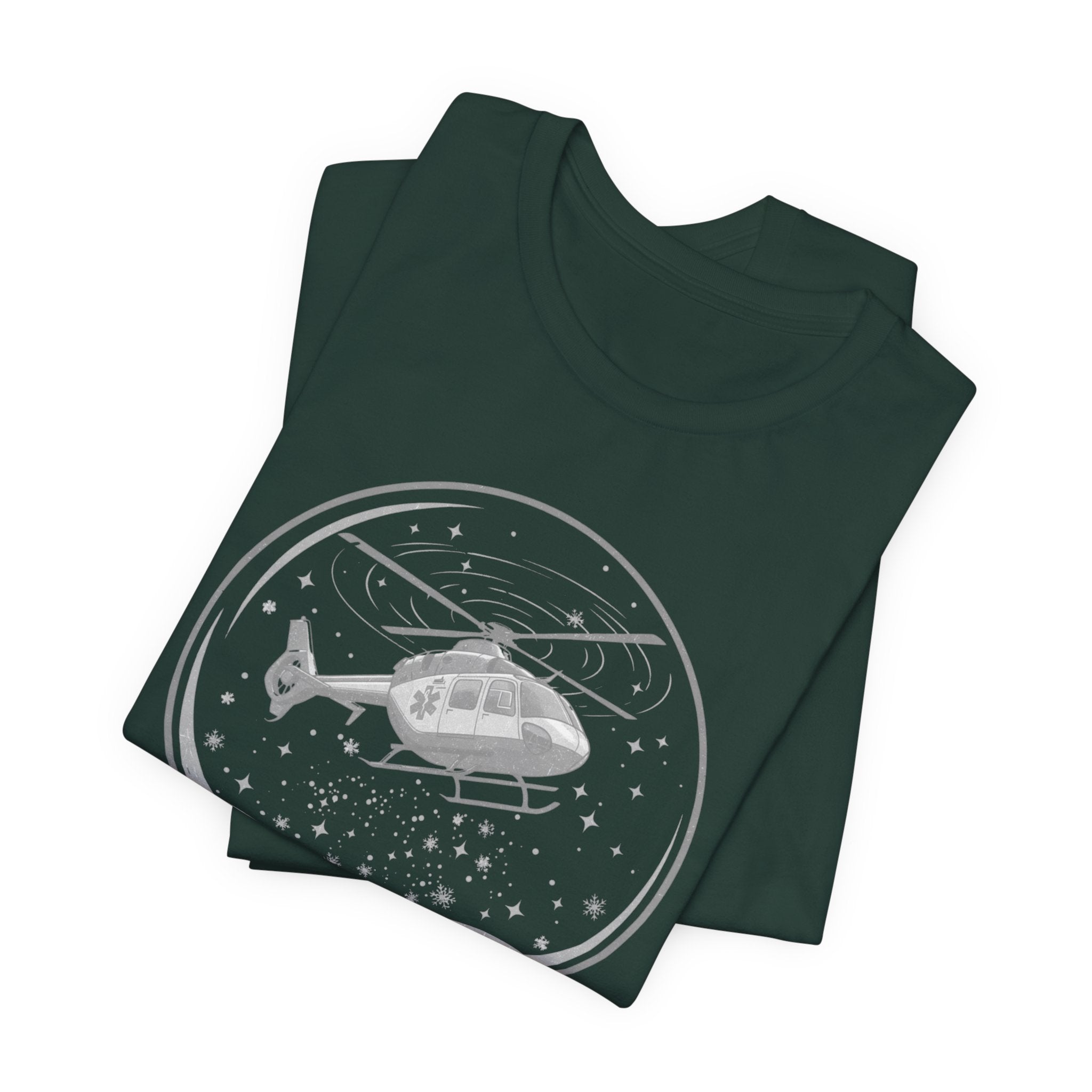 Folded dark green t-shirt with a graphic of a helicopter in a snow globe and text "Heli-bells ring: certified for the holidays" by Rotor Wash & Wear