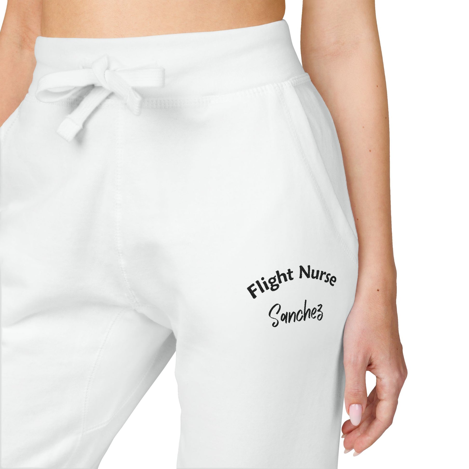 White joggers with embroidered 'Flight Nurse Sanchez' text on the thigh against a white background