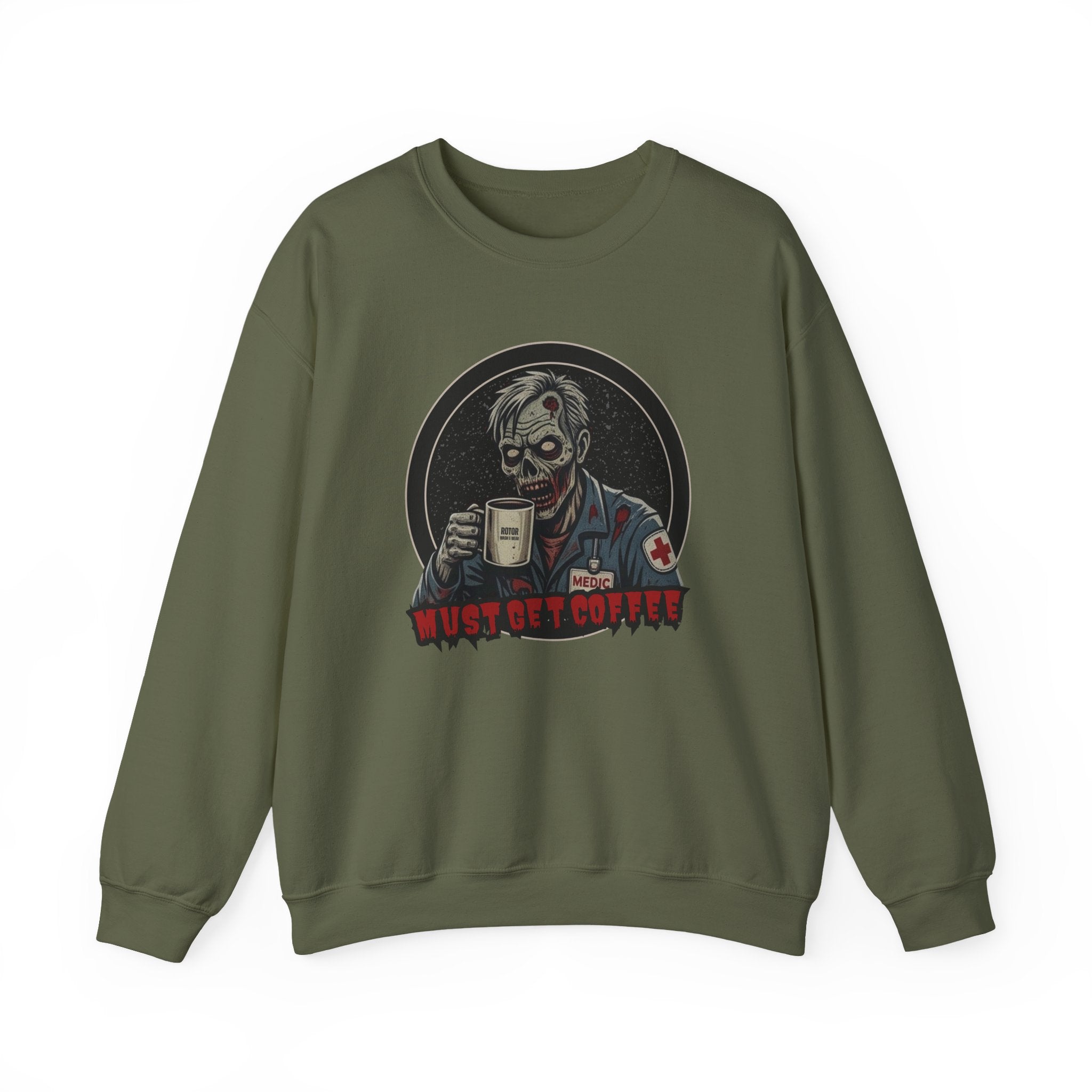 A military green crewneck sweatshirt featuring a graphic print of a zombie in a medical uniform holding a coffee mug, with the text 'MUST GET COFFEE' below it by Rotor Wash & Wear