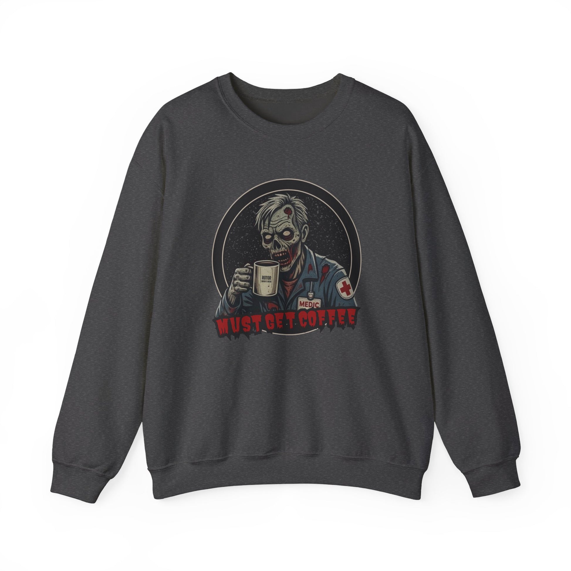 A dark gray heather crewneck sweatshirt featuring a graphic print of a zombie in a medical uniform holding a coffee mug, with the text 'MUST GET COFFEE' below it by Rotor Wash & Wear
