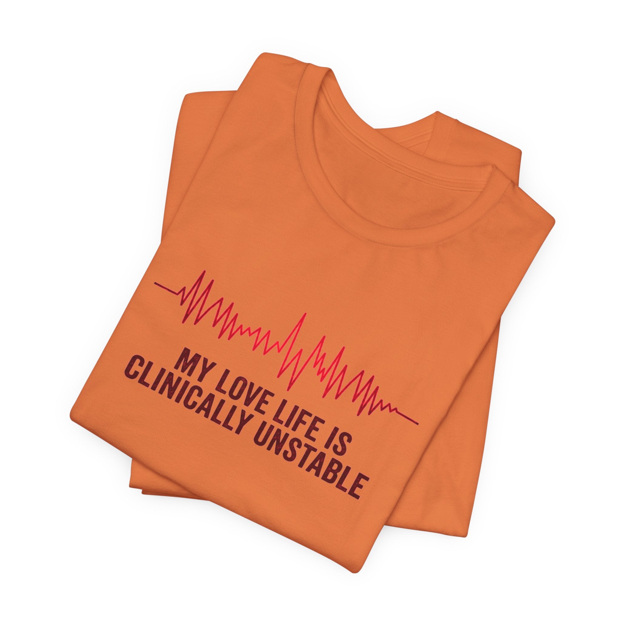 Folded burnt orange t-shirt ventricular fibrillation cardiac rhythm and text "My love life is clinically unstable" by Rotor Wash & Wear