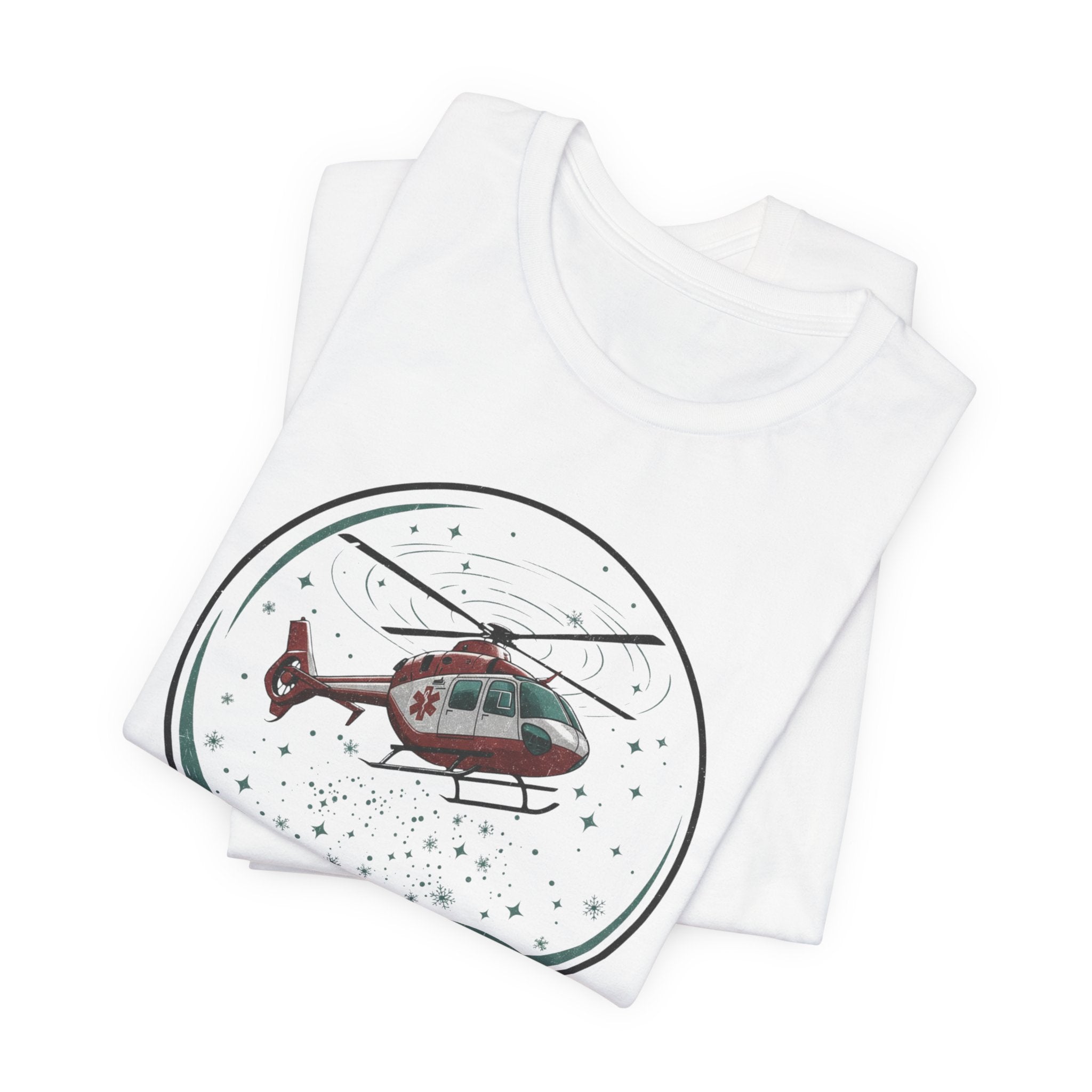 Folded white t-shirt with a graphic of a helicopter in a snow globe and text "Heli-bells ring: certified for the holidays" by Rotor Wash & Wear