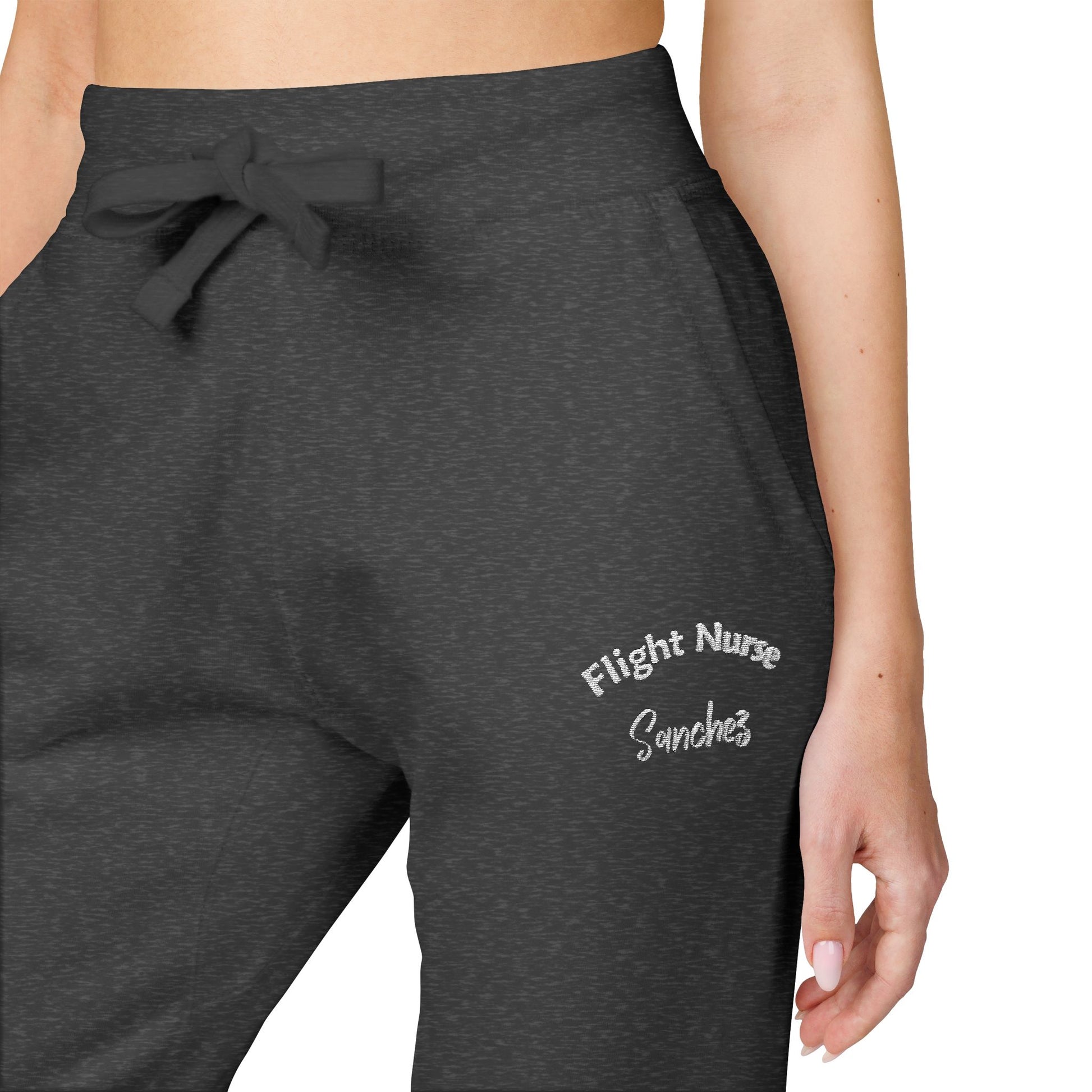 Dark gray joggers with embroidered 'Flight Nurse Sanchez' text on the thigh against a white background