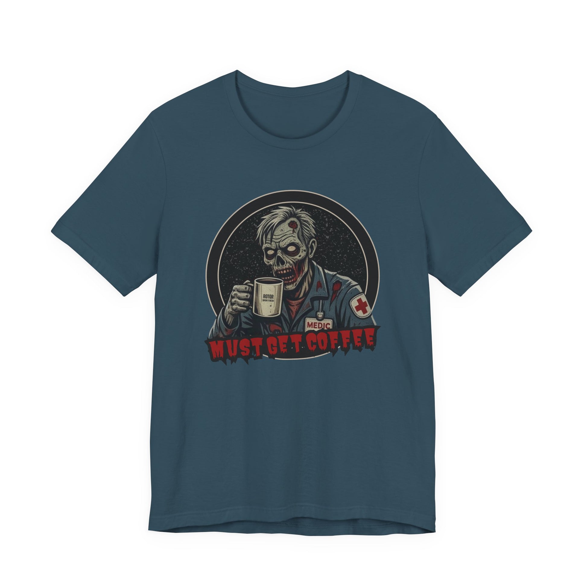 A dark teal crewneck t-shirt featuring a graphic of a zombie medic holding a coffee mug with the text 'MUST GET COFFEE!' in red by Rotor Wash & Wear