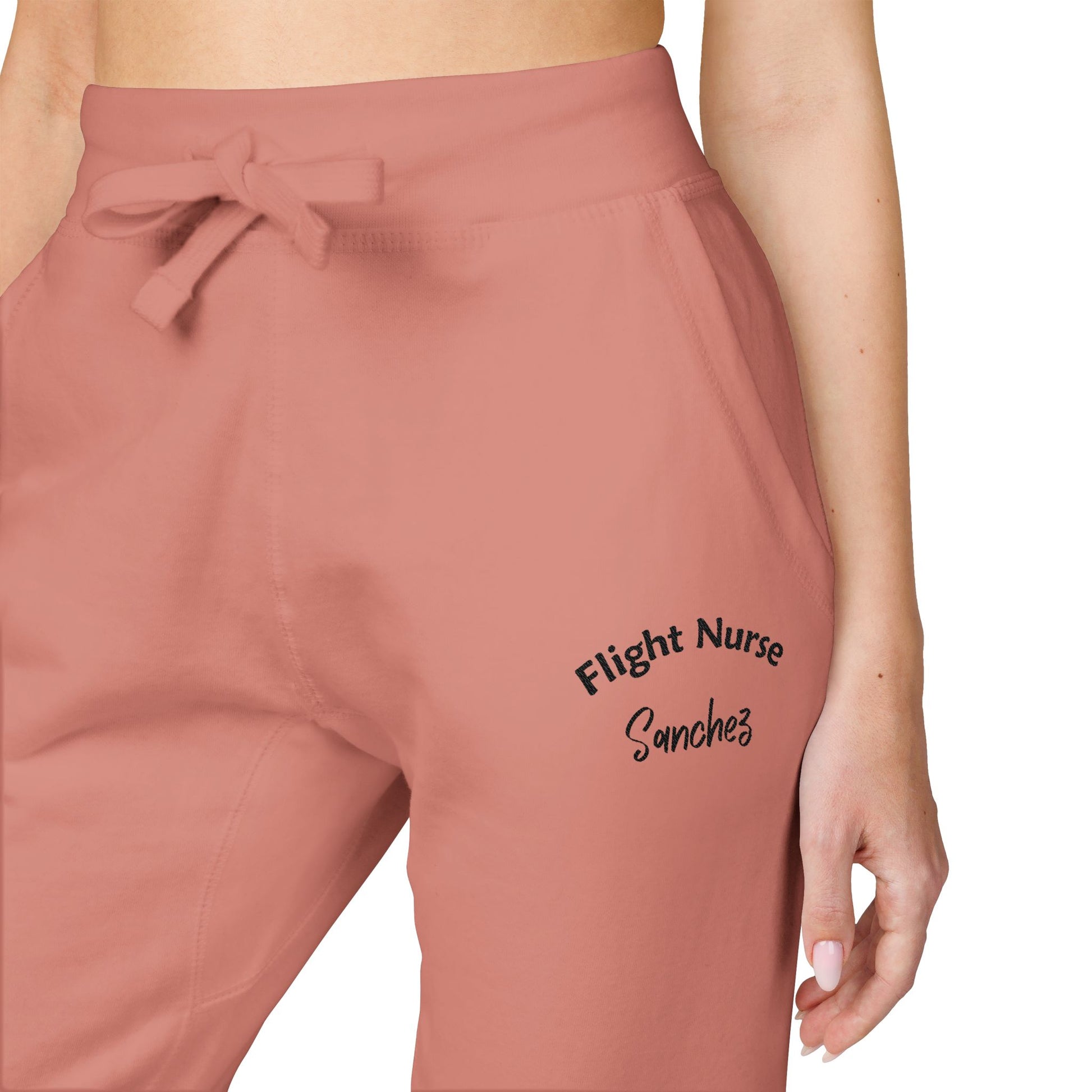 Pink joggers with embroidered 'Flight Nurse Sanchez' text on the thigh against a white background