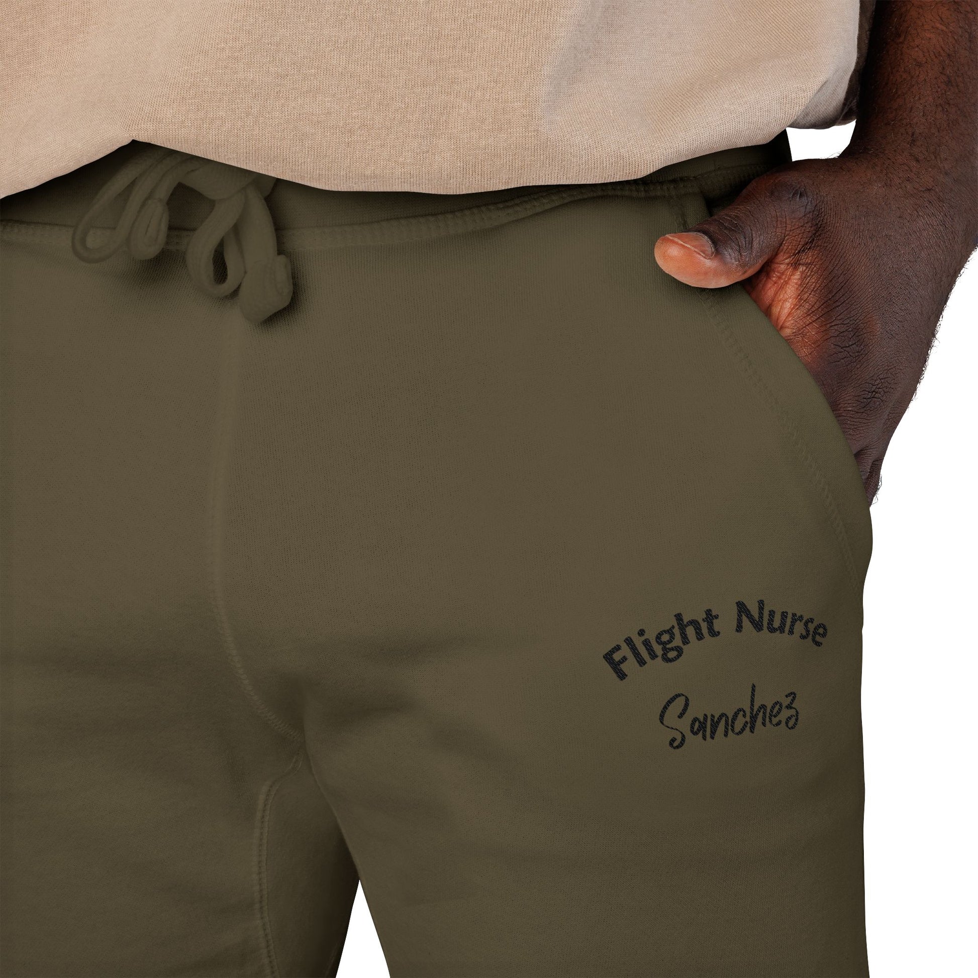 Olive green joggers with embroidered 'Flight Nurse Sanchez' text on the thigh against a white background