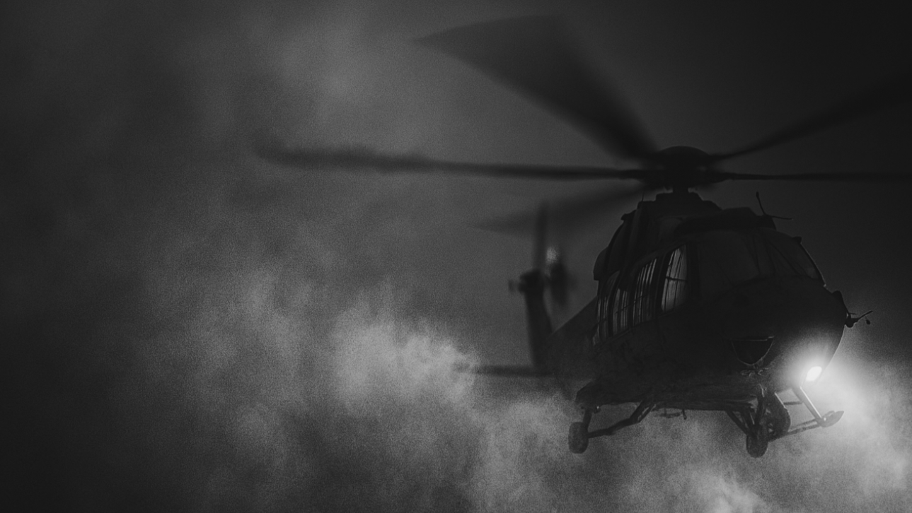 Silhouette of a helicopter in flight with light smoke against a dark background
